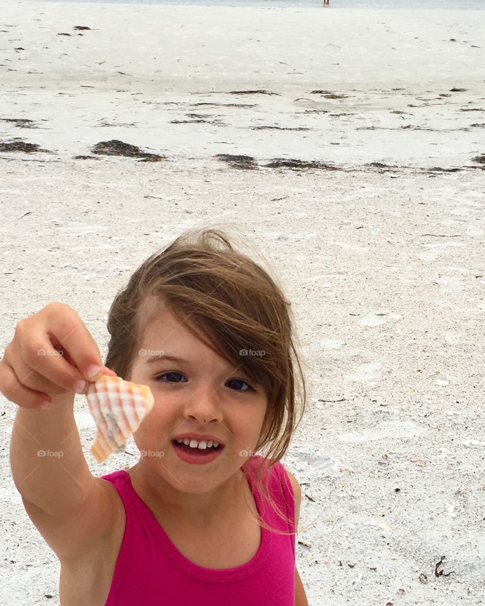 Close-up of a cute girl holding seashell in hand