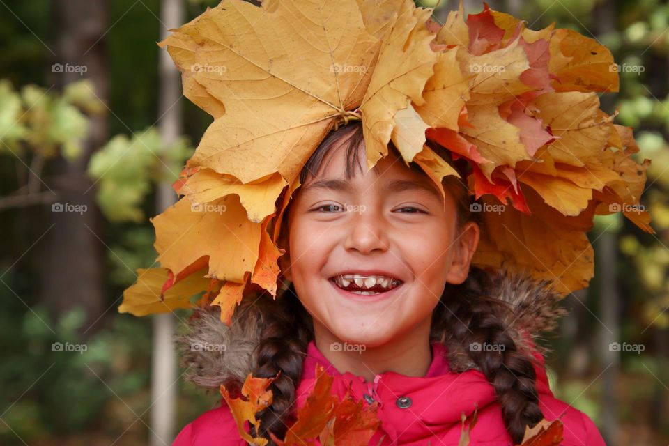 Happy cute girl in an autumn leaves crown