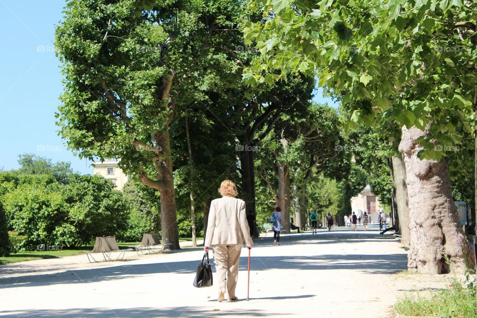 An old lady is walking in the botanic park in Paris, France.