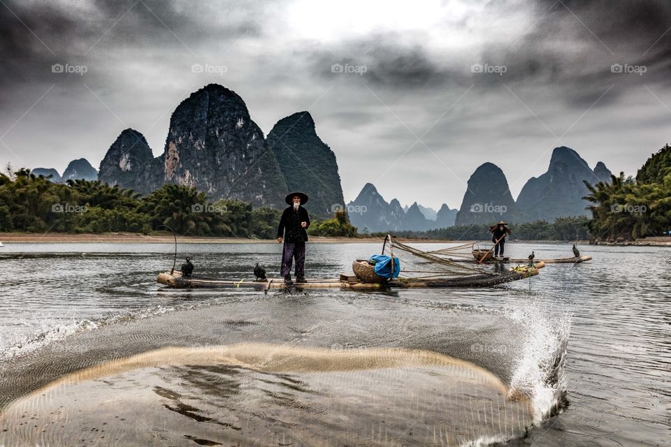 Guilin cormorant fisherman casts his net