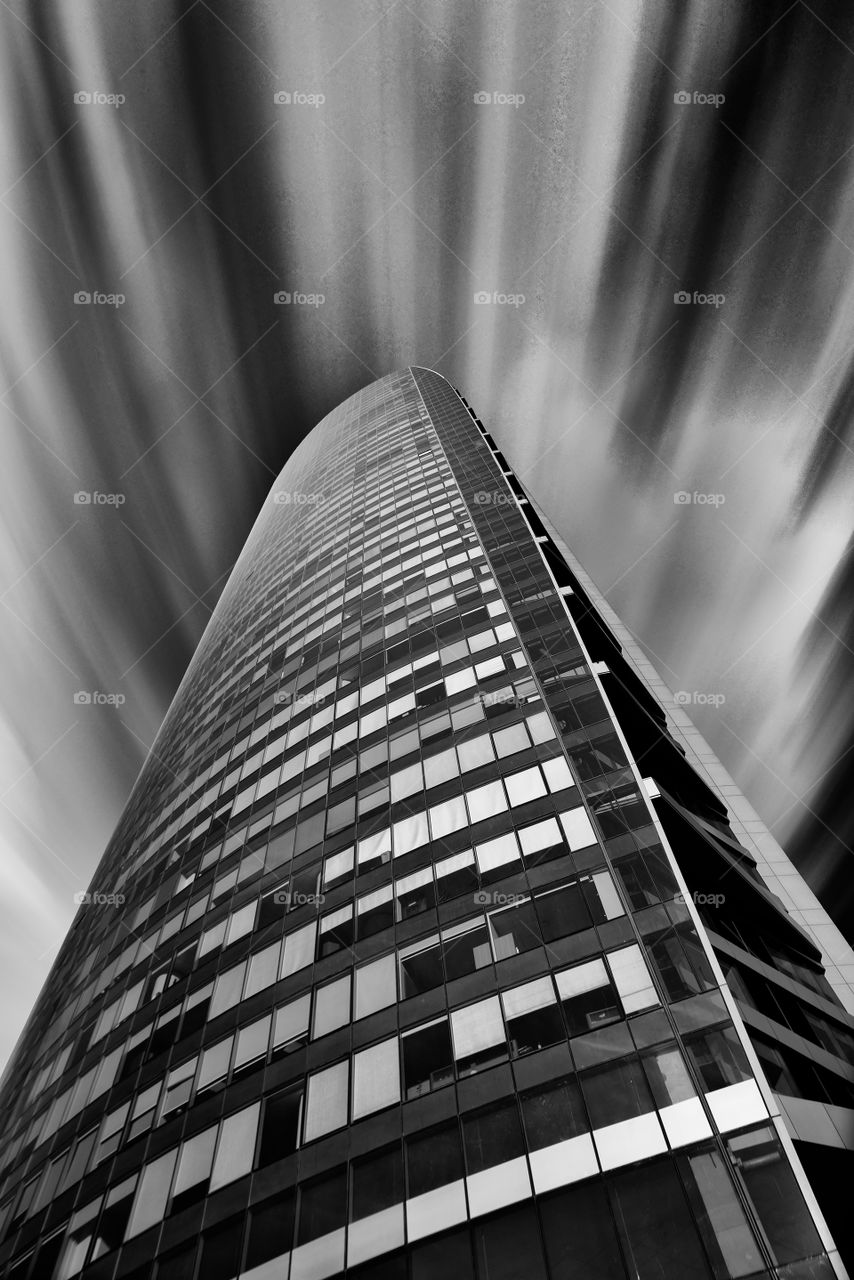 tower seen from below, in long exposure with black and white leaking clouds