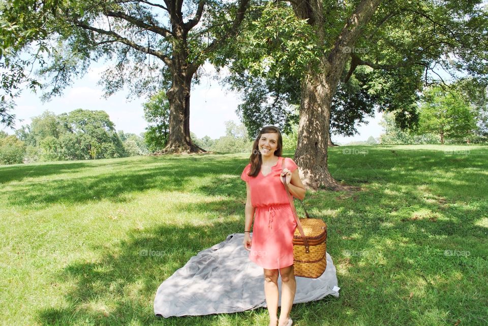 Happy woman standing in park holding bag