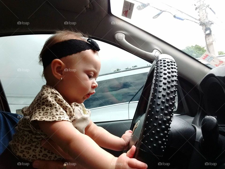Bebê no volante do carro, "dirigindo".