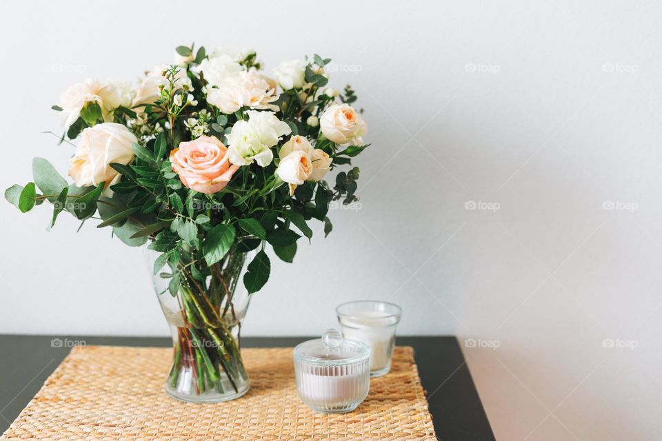 Bouquet of different flowers roses in vase on table at home 