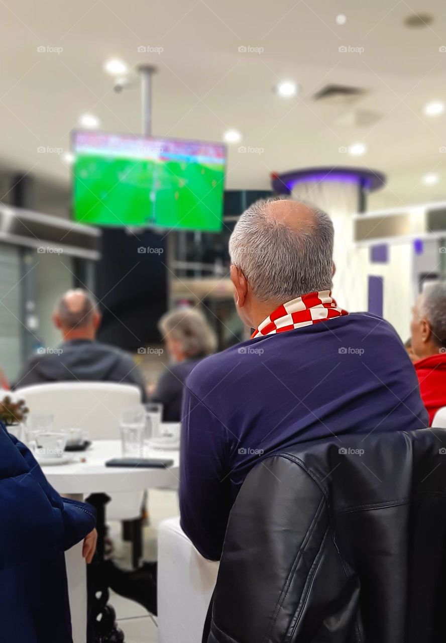 Soccer fan's watching game on TV with shawl