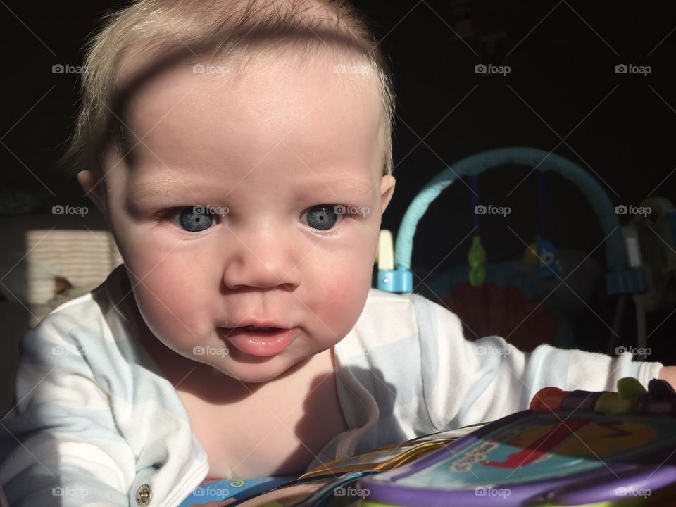 Cute baby boy in awe playing with toy