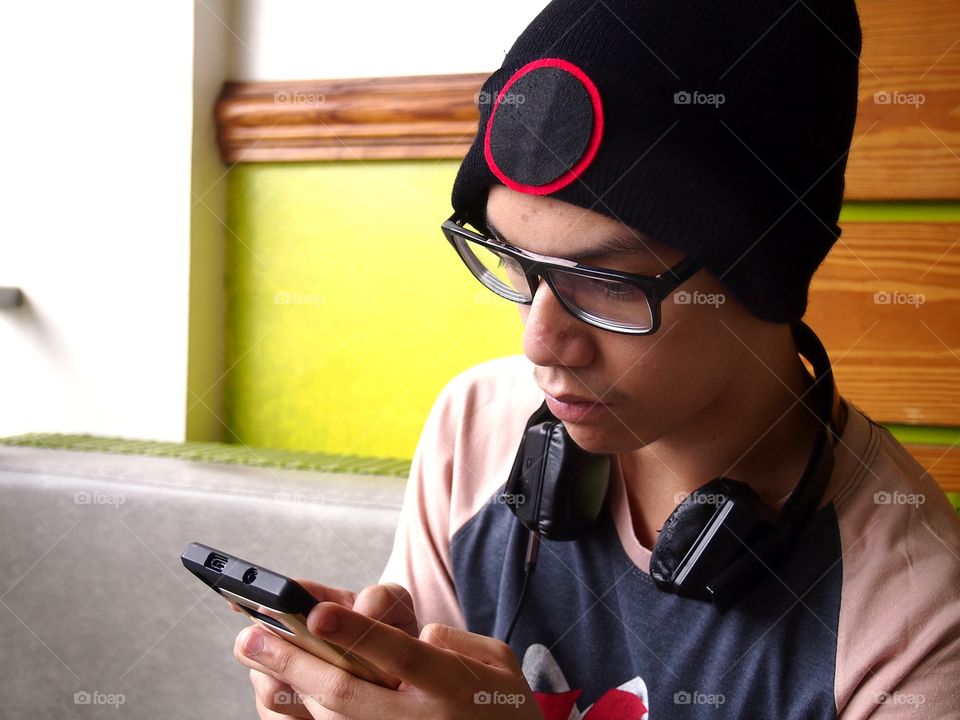 teenage boy wearing bonnet using a smartphone