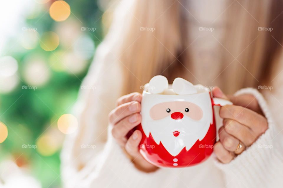 Woman holding cup of cocoa with marshmallow 