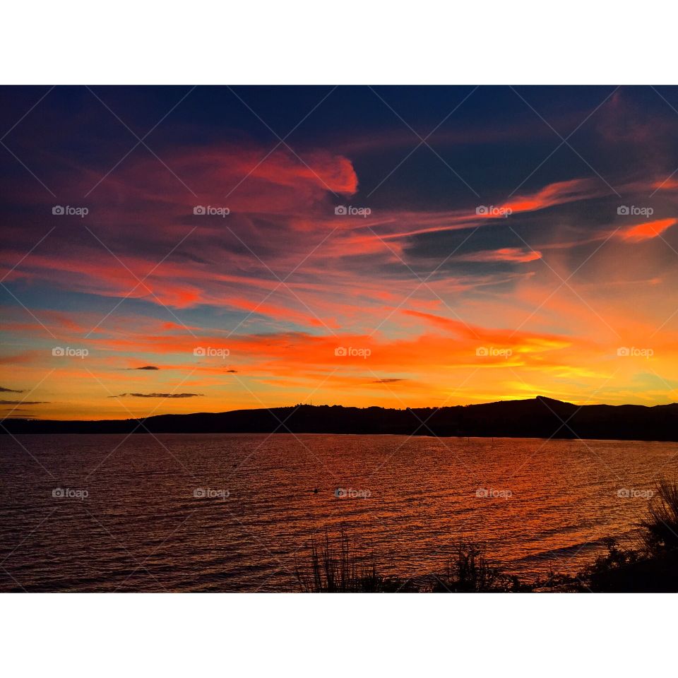 Summer sunset of lake Taupo, on the north island in New Zealand. Lots of colours as the sun hides behind the volcanoes across the lake.