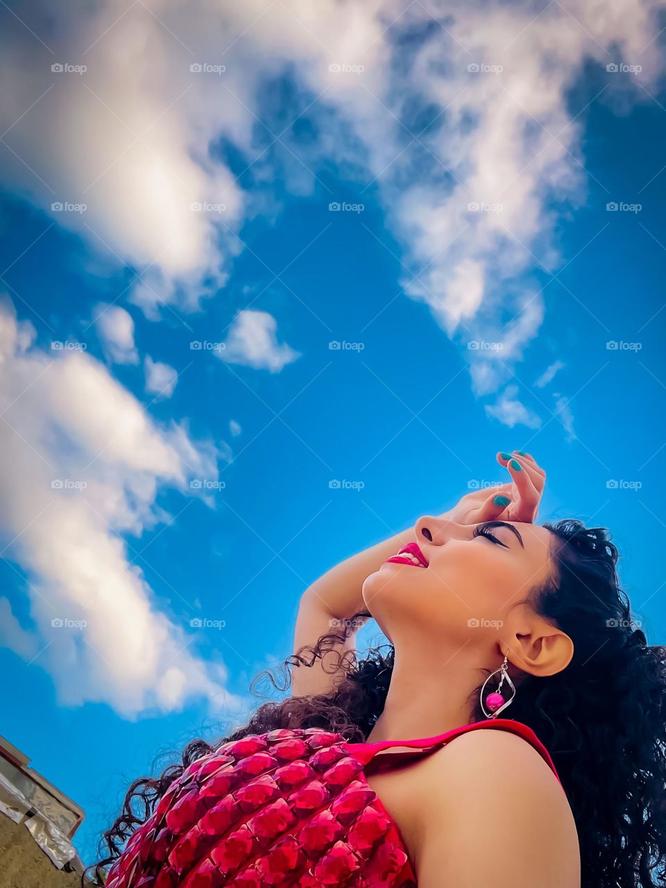 Girl with curly hair and clouds in the blue sky