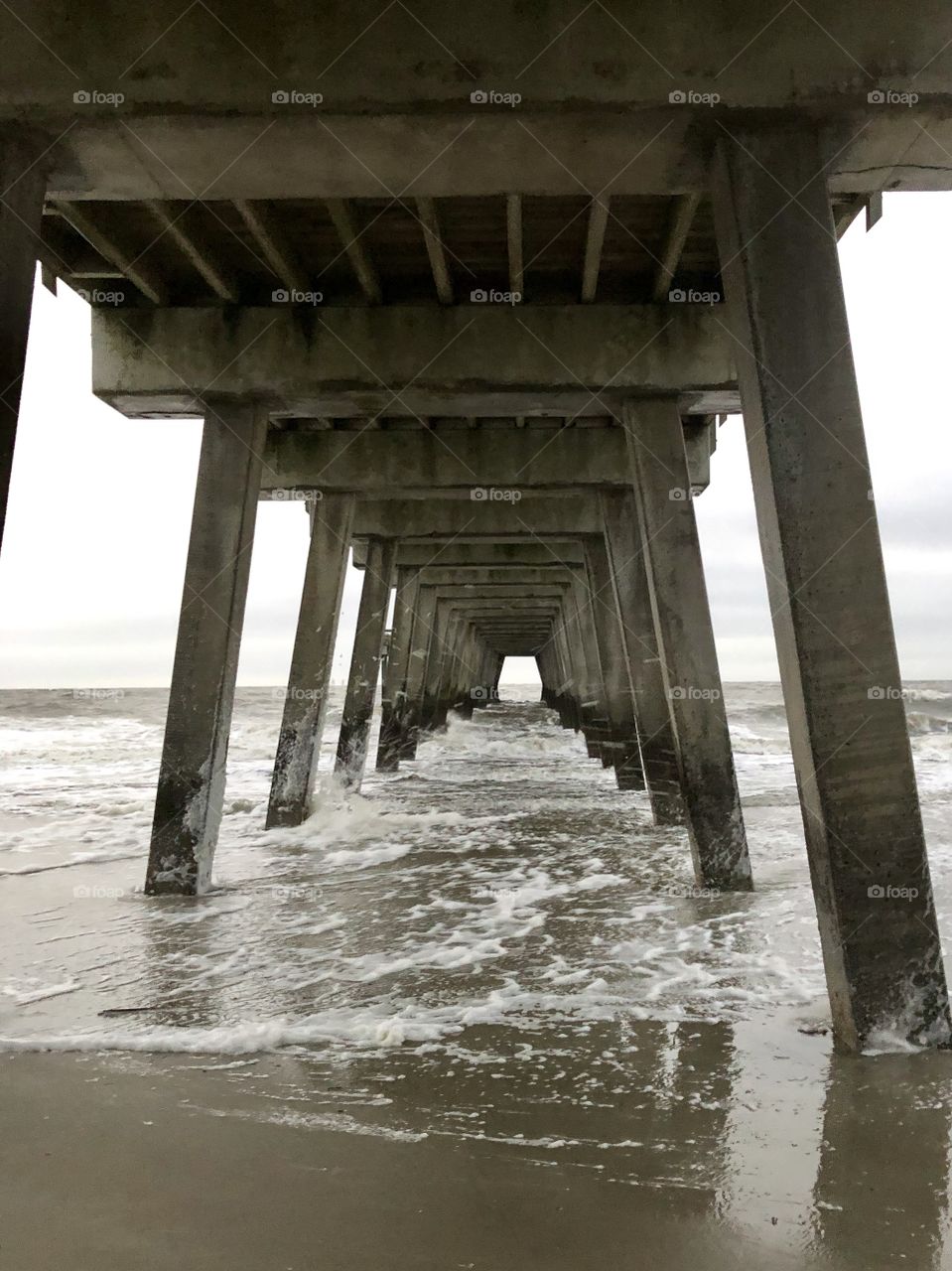 Under the Tybee Island Pier, I gaze at the reflections swirling with the cold salt water waves as scouring sand scrapes my skin. 