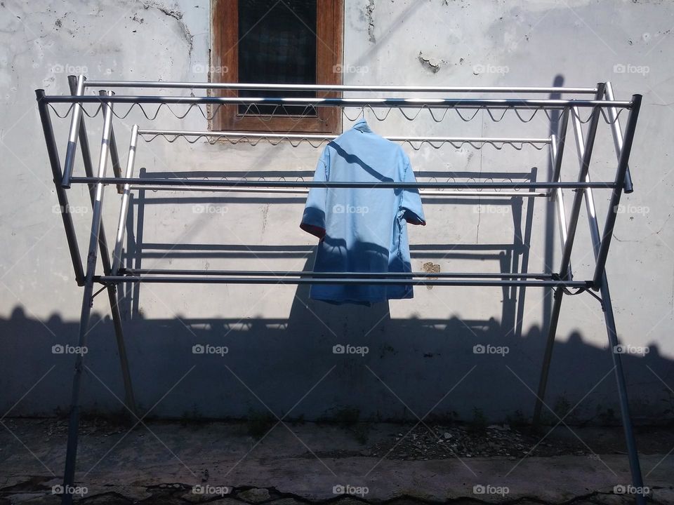 clothes dryers made of aluminum pipes are being used to dry uniforms in the yard.