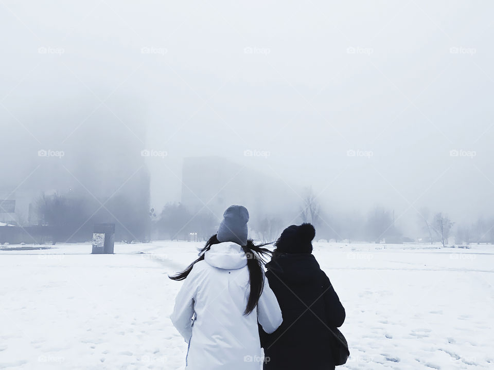 Two people walking in the misty evening city 