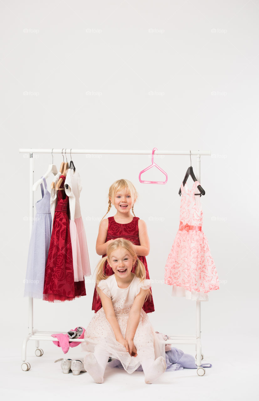 Two cute sisters is posing and playing with clothes and having fun.