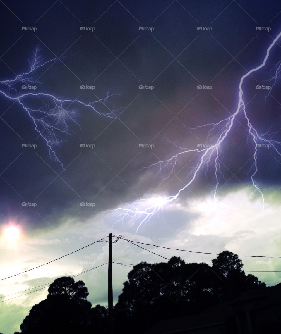 Lightning strikes across the sky at sunset.