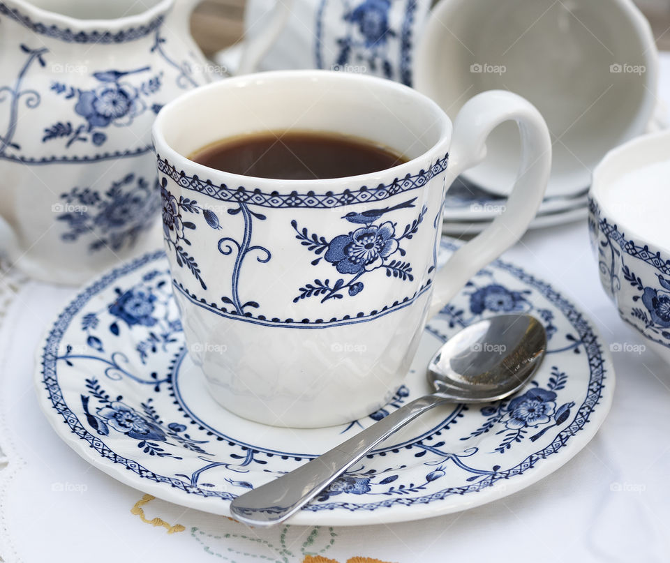 Strong hot black tea in a blue and white patterned cup and saucer with a milk jug and sugar bowl.