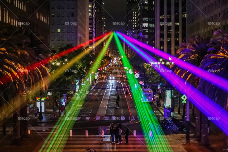 San Francisco Pride 2023 laser light display of the pride flag colors illuminating the sky in front of the Ferry Building on the Embarcadero looking down market street 