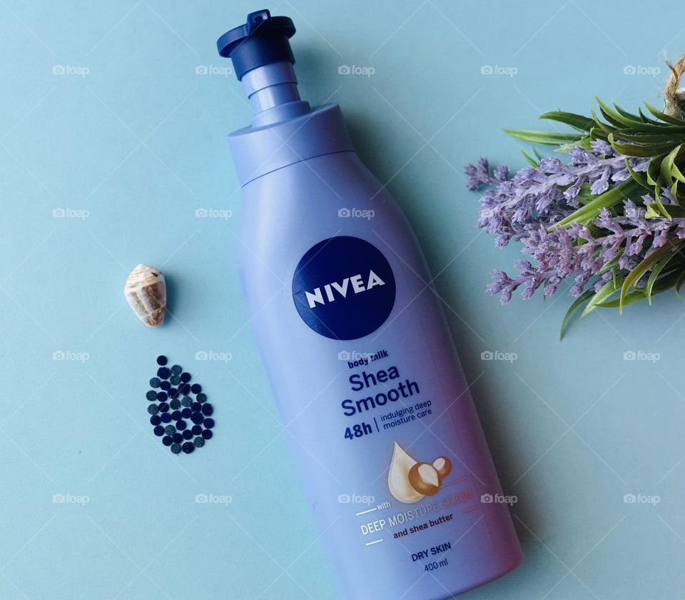 Nivea body lotion and blue background and lavender flowers and shell drop.