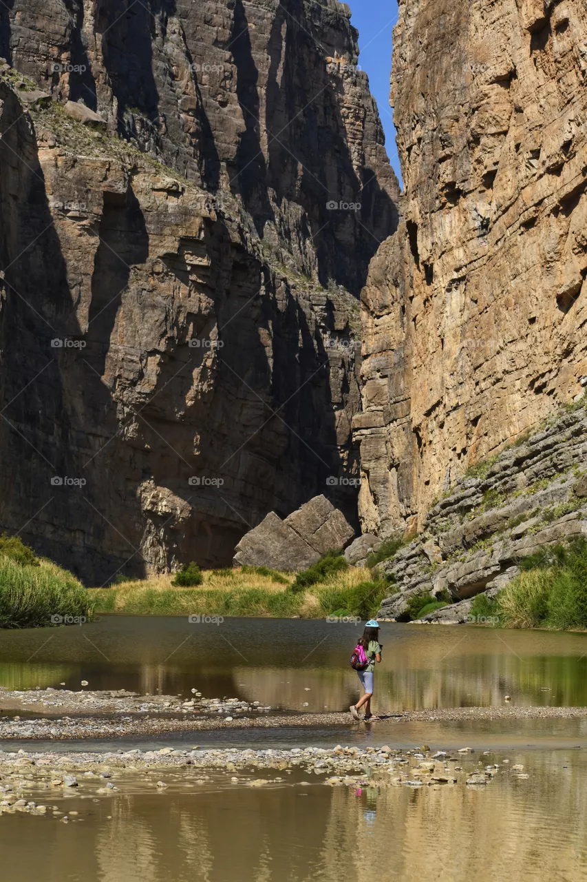 Summer is exploring national parks. A young girl exploring Santa Elena Canyon at Big Bend National Park.