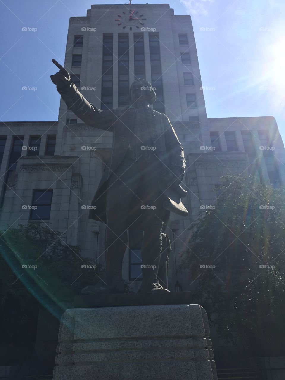 Statue standing tall in front of city hall as the rays of the sun beam down on time in Vancouver, British Columbia 