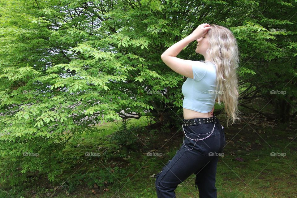 Girl with long blonde hair in summer with greenery background