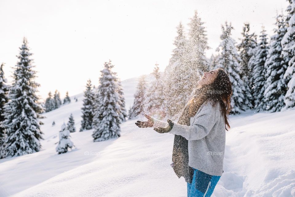 Woman playing in the snow, while being in the mountains in a snowy landscape.