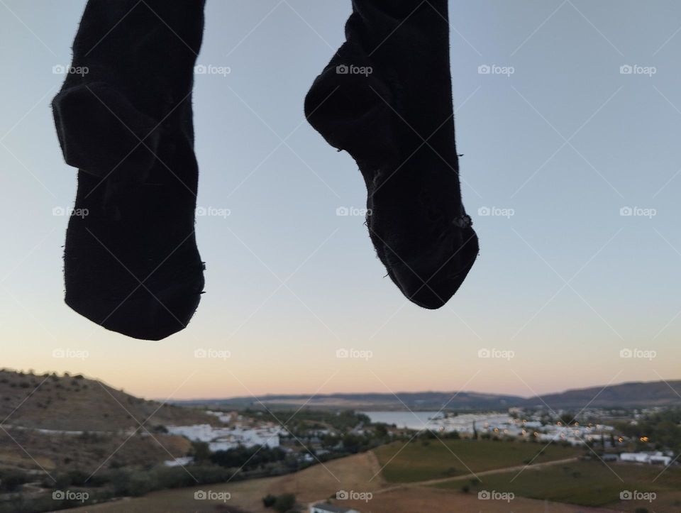 Two black socks are hanging in the air in front of a beautiful landscape