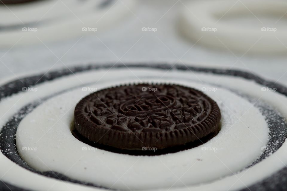 Adding the finishing touch to a cake .. iced in black and white and the centre circle being an Oreo Biscuit