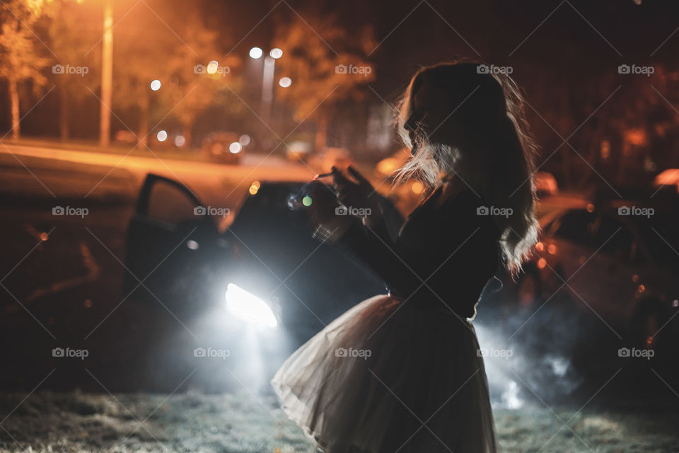 woman wearing ballet tutu in the car lights at night
