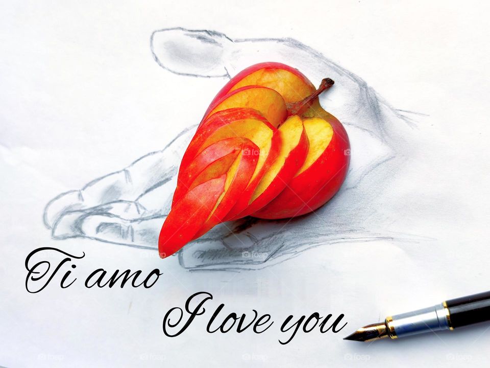 Symbol of love. A man's hand is drawn on a white sheet with a black pencil. On the hand lies a red apple in the shape of a heart. Under the drawing of the hand lies an ink pen. The sheet has the inscriptions: "I love you" in Italian and in English