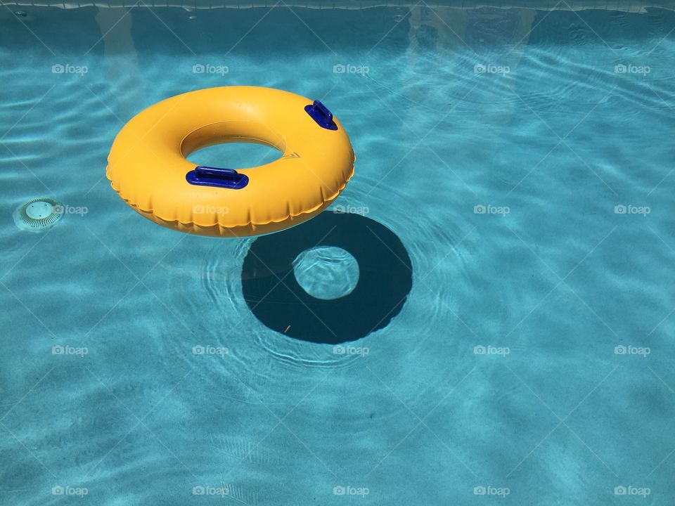 Inflatable yellow inner tube floating in clear blue waters