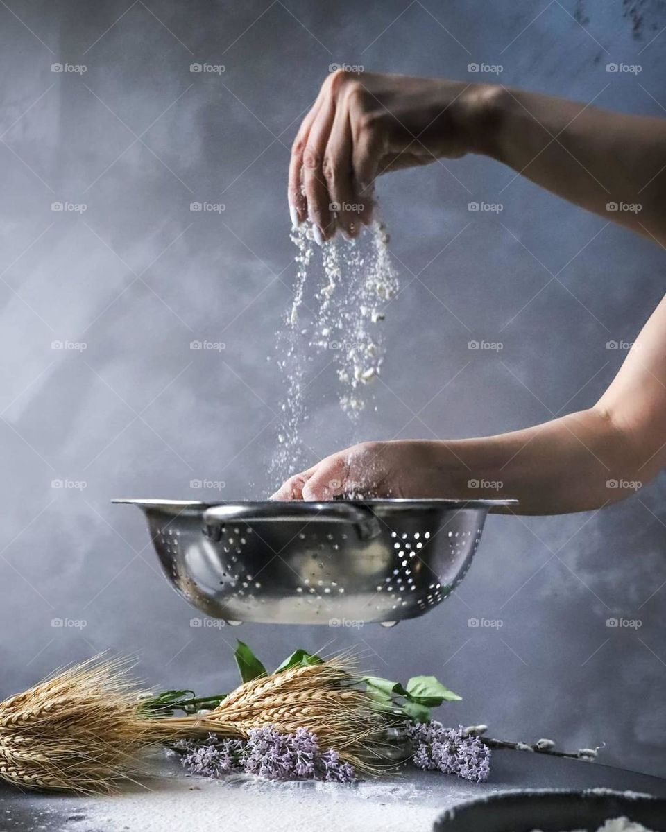 Throws the future dough for the pie on the table with flour and flowers from above with his right hand into the grater