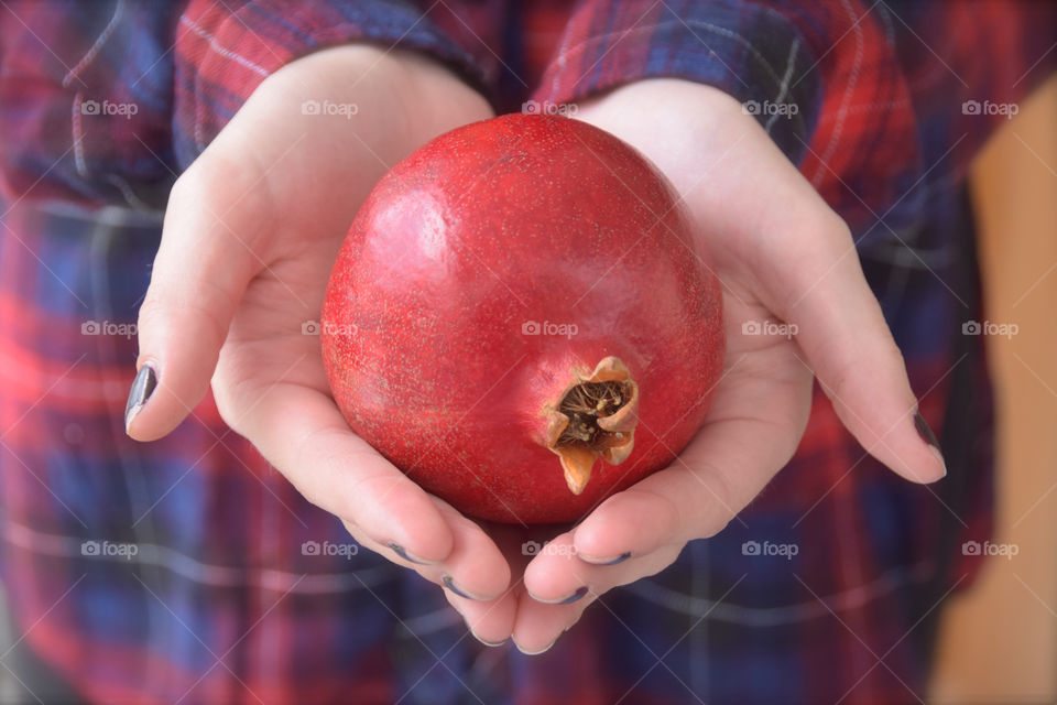 Pomegranate in outstretched open hands of girl