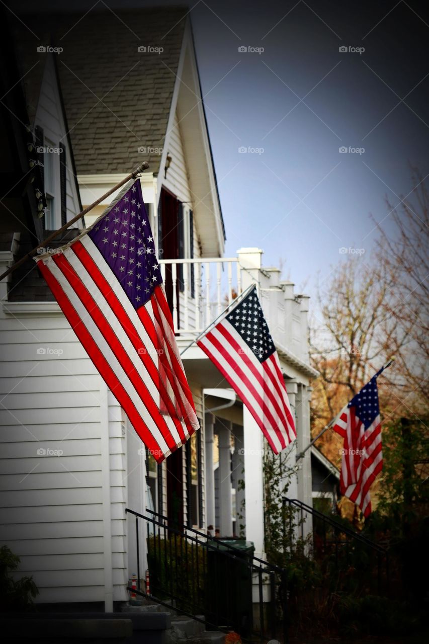 A row of historic houses line the street in Steilacoom, Washington with American flags waving in the breeze. 