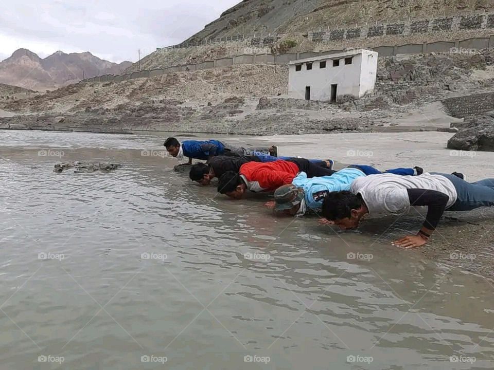 Some boys doing pushups on the river bank.