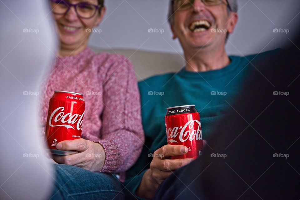 Couple watching television with two cokes