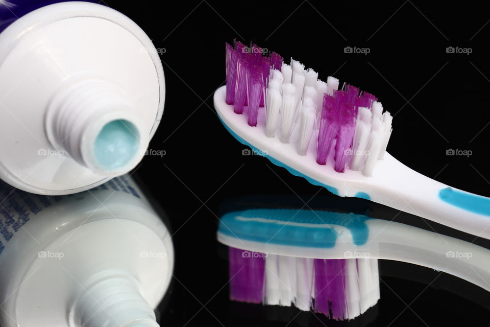 Toothbrushes and toothpaste on a mirror shelf. Oral hygiene products. Toothbrush - a device for cleaning teeth and gums massage.