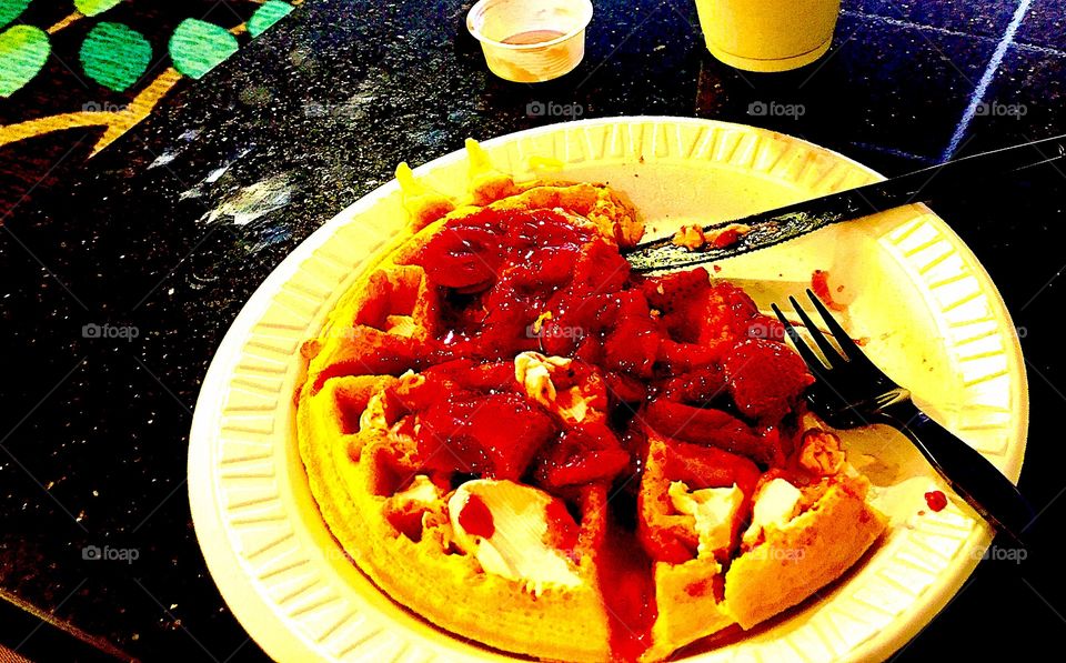 Delicious Griddle made waffle with red strawberry glaze, pink softened strawberry cream cheese, with Milk in a quiet breakfast hotel nook
