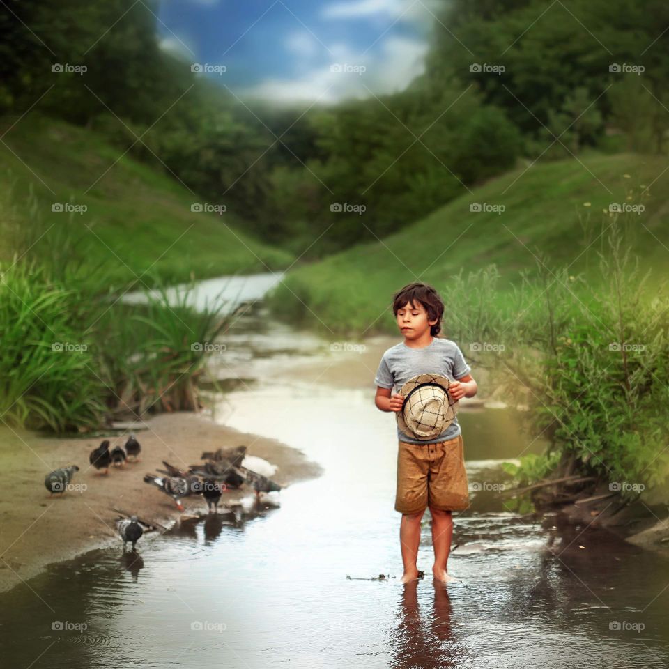 Boy with hat on the water searching something 