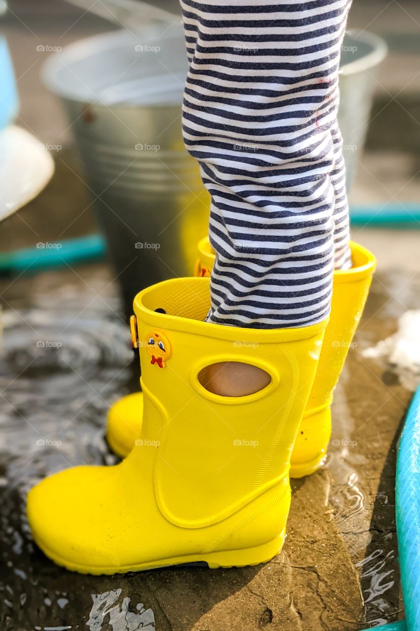 Kid's feet in yellow rubber rain boots