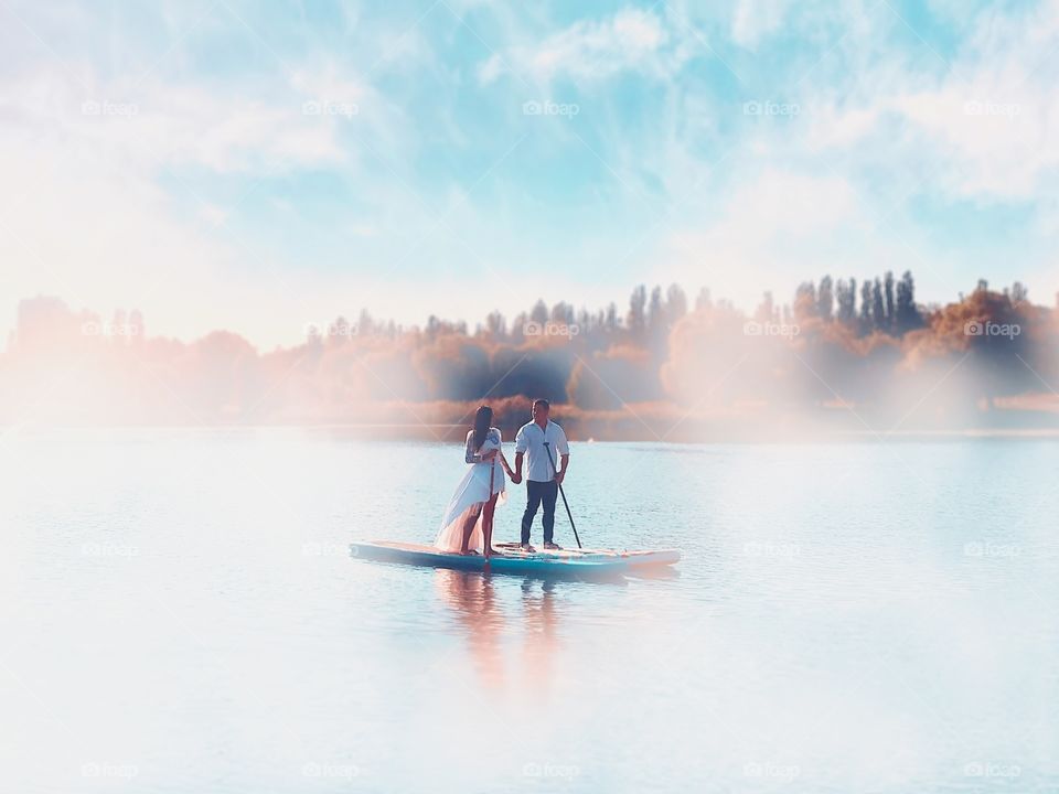 Couple standing on the paddle board in the middle of the lake 