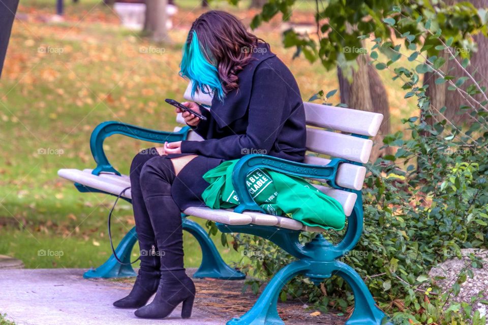 Woman with a bright green strands of hair in a park