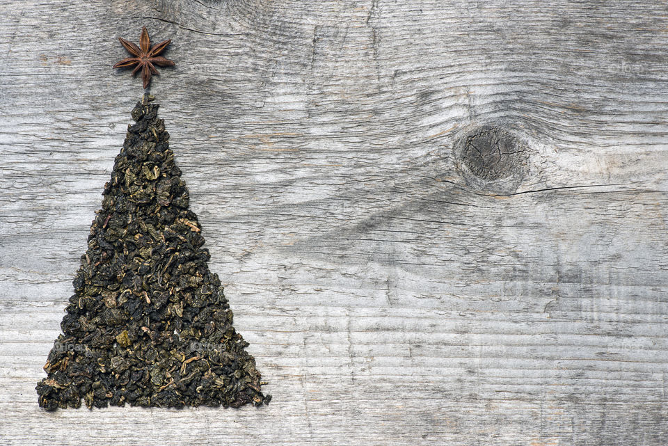 Christmas greeting card made of green tea and star anise on old wooden background