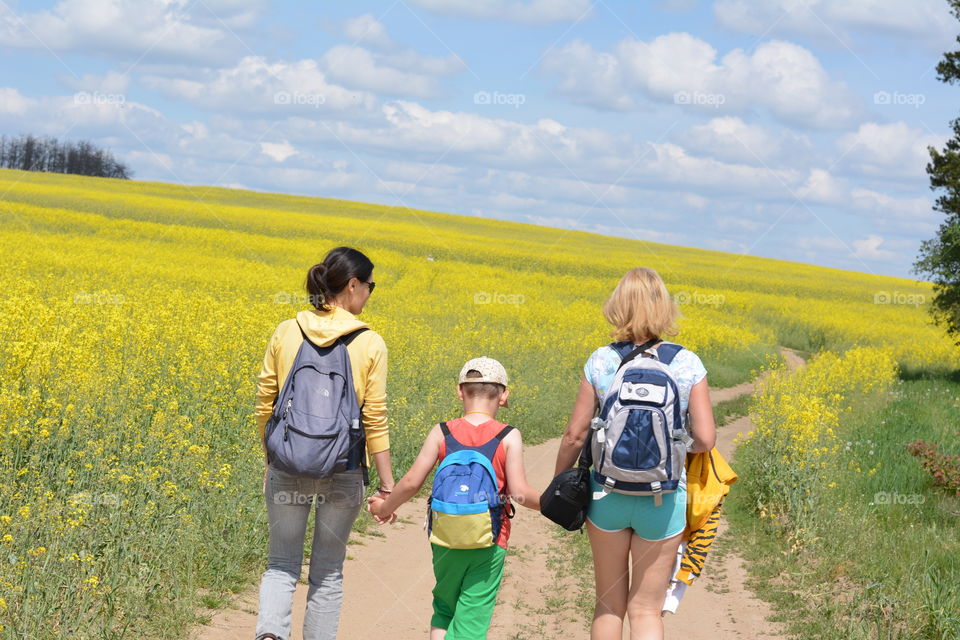 people walking on a road rapeseed yellow flowers field adventure travel summer time