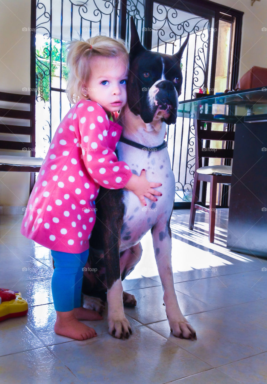 Little girl hugging her loving boxer dog