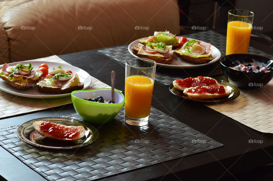 healthy breakfast full of vitamins - sandwitches of wholemeal bread with fresh lettuce, cheese, ham, egg, cress and cherry tomatoes plus yogurt with fresh fruit strawberries and blueberries and scones with jam plus freshly squeezed orange juice