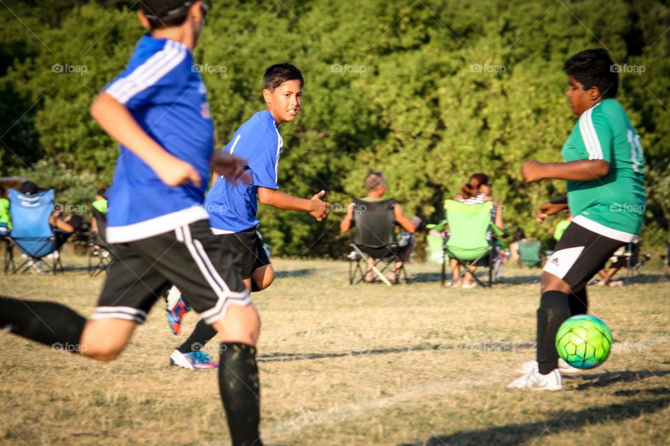 Happy kids are playing soccer outdoors