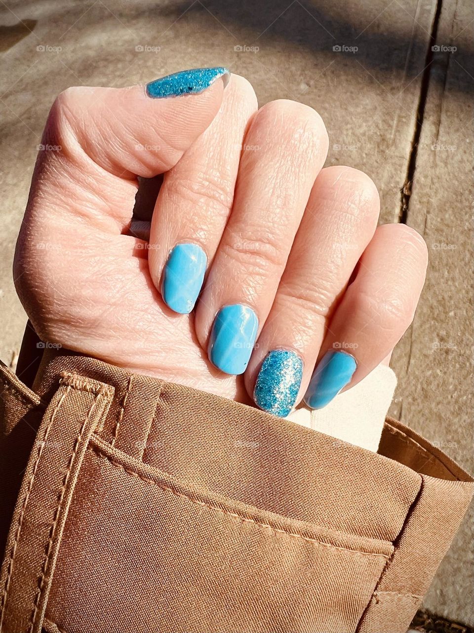 Soft blue glittery gel nail art manicure in the sun