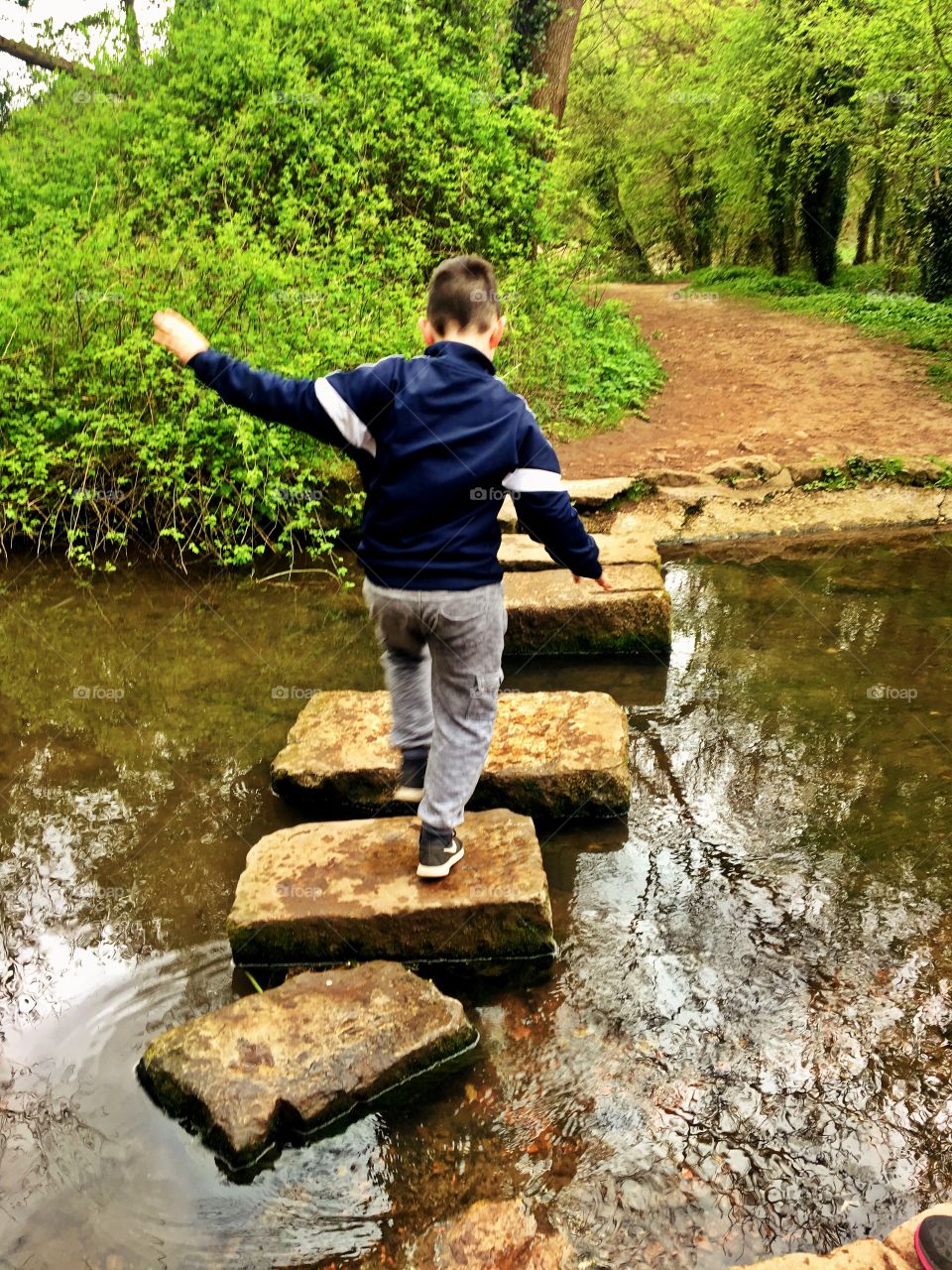 Boy crossing a river on stepping stones