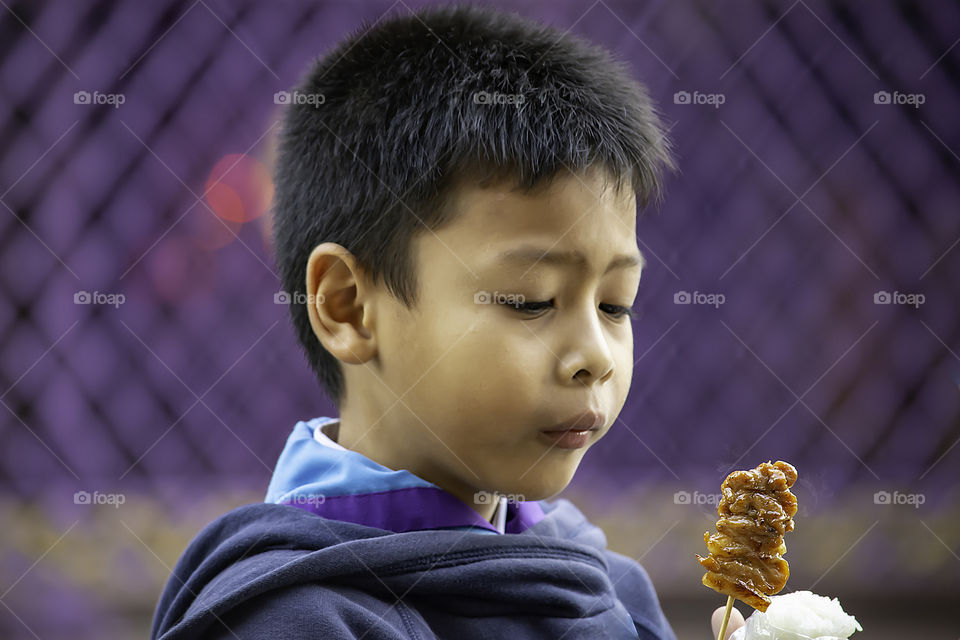 Asian boys are eating sticky rice and pork roast , The food is simple and popular to eat breakfast in Thailand.